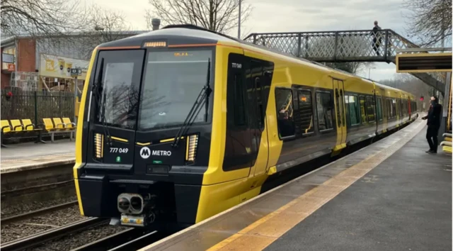 A yellow train pulls into a station