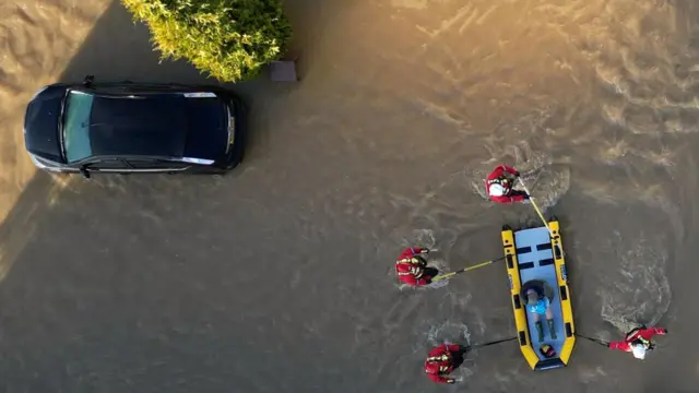 Rescue team guiding kayak with a person through flooded caravan park