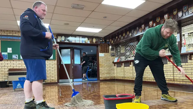 Two men mopping the floor at Syston Rugby Club