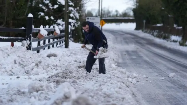 A man clears snow in Towlerton, County Laois in Ireland on 6 January