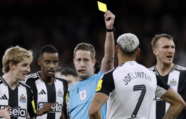 Newcastle United's Joelinton is booked by referee John Brooks