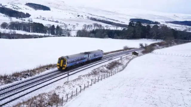 Train driving through snowy scener