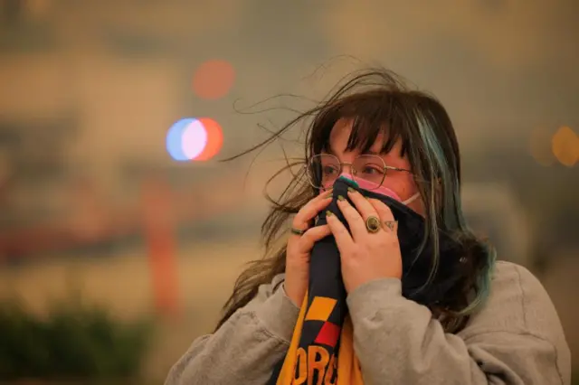 A woman covers her nose with a scarf