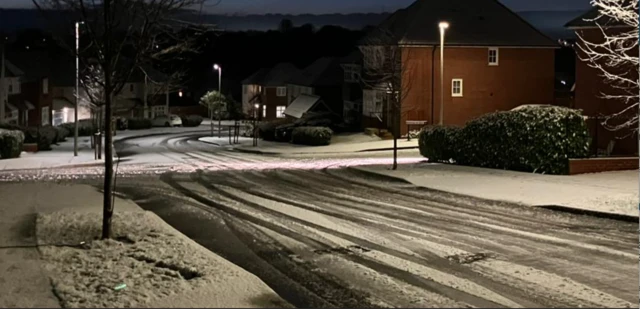 Snow covering pavements and a road with car tracks in the snow