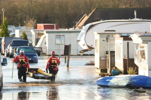 Two rescuers entering water with a rubber boat