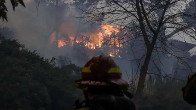 Firefighters below a burning home