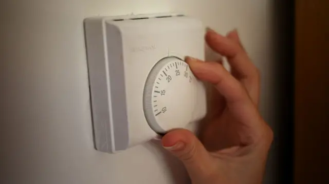 File photo dated of a general view of a central heating thermostat, with someone turning it with their hand.