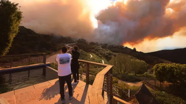 People watch the fire from a balcony