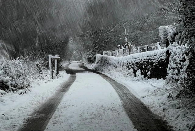 A snow covered road in Stockport with tyre tracks down the middle