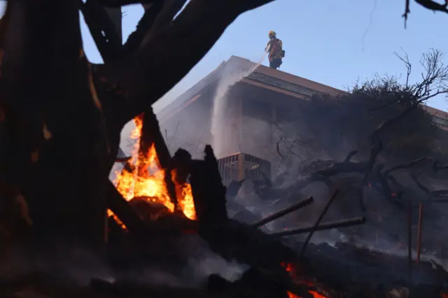 Firefighters extinguish flames of a fire from the roof of a house that was ablaze.