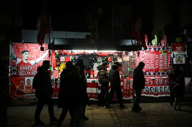 Fans walk past a scarf stall