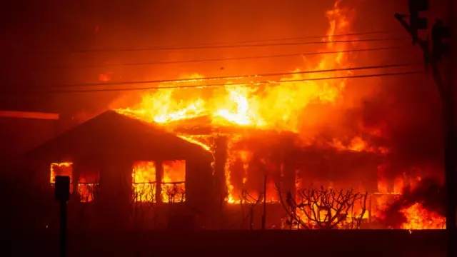 Fire engulfs a structure as the Palisades Fire burns during a windstorm on the west side of Los Angeles