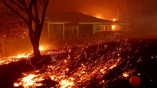 Grass in front of house on fire, flames seen throughout