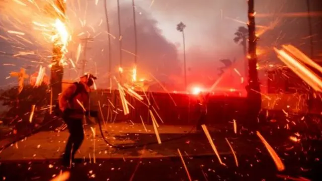 Firefighters battle the Palisades Fire as it burns during a windstorm on the west side of Los Angeles, California