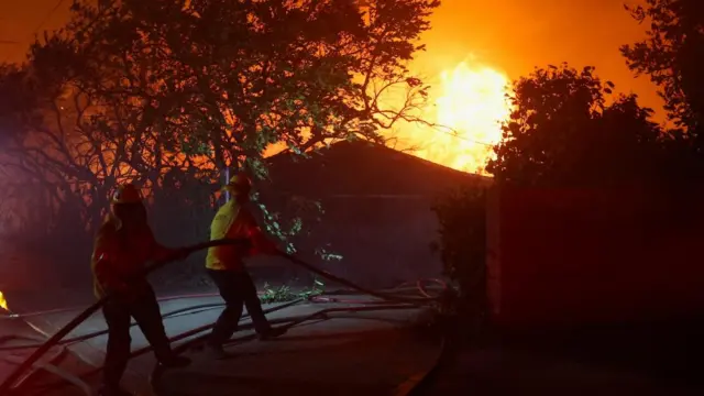 Firefighters work to extinguish flames as the Eaton Fire burns in Pasadena