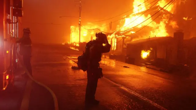 Firefighters tackling the Palisades wildfire as it burns multiple structures along the Pacific Coast Highway in Malibu, California