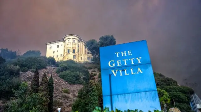 The Getty Villa Museum sits on top of a hill with smoke rising in the background