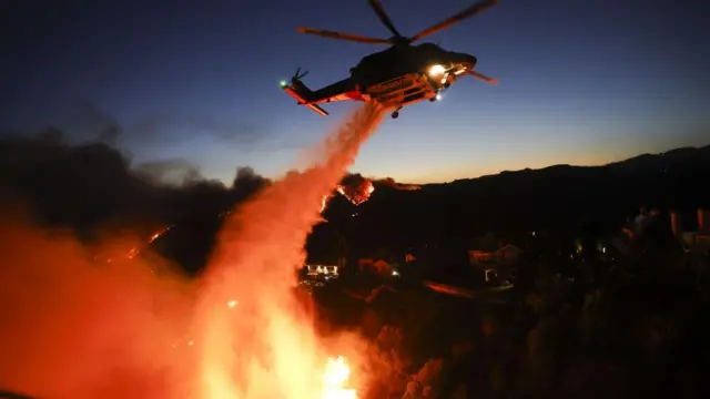 A Los Angeles County firefighting helicopter drops water to extinguish the Palisades wildfire.