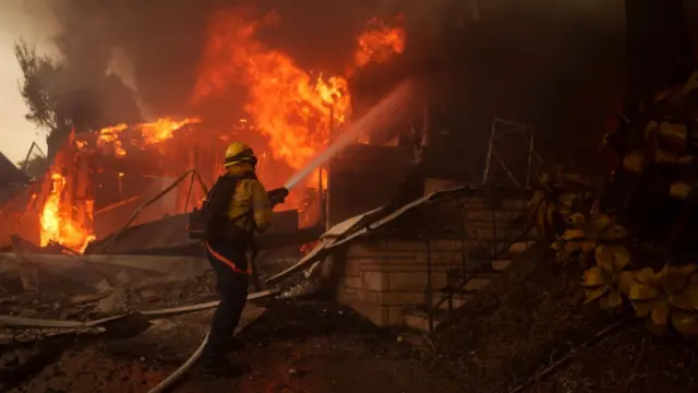 A firefighter battles flames from the Palisades Fire on January 7, 2025 in the Pacific Palisades neighborhood of Los Angeles, California.