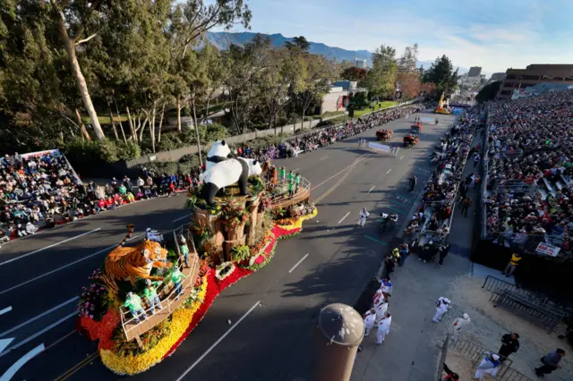 Parade float, stands with watchers, mountains in background