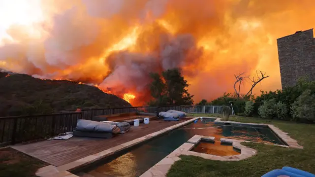 A brush fire burns near homes in Pacific Palisades, California on January 7, 2025.