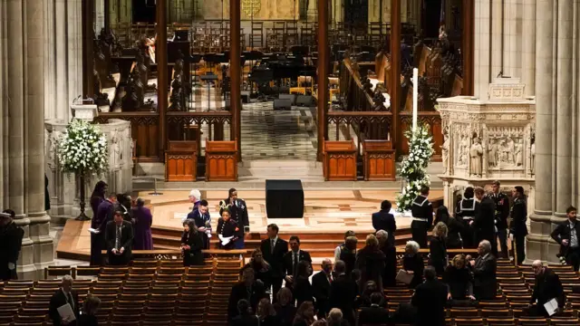 Closer view of mourners in National Cathedral hall. a space for the casket rests in the middle