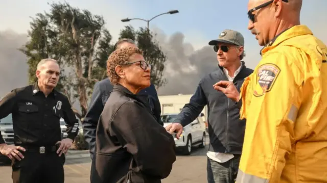 Los Angeles Mayor Karen Bass (2-L front) and California Governor Gavin Newsom (2-R) get a briefing about an area damaged by the Palisades wildfire