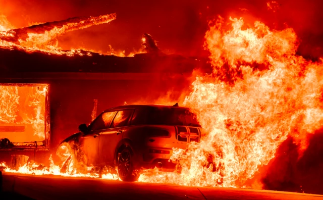 A car and home burn during the Eaton fire in the Altadena area of Los Angeles County.