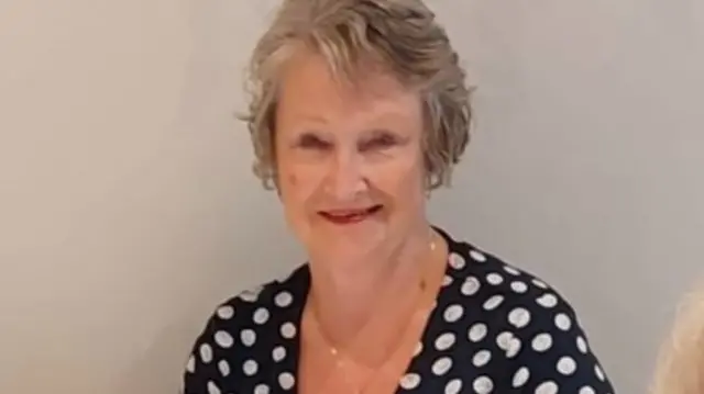 Linda sits at a table in a black and white dress