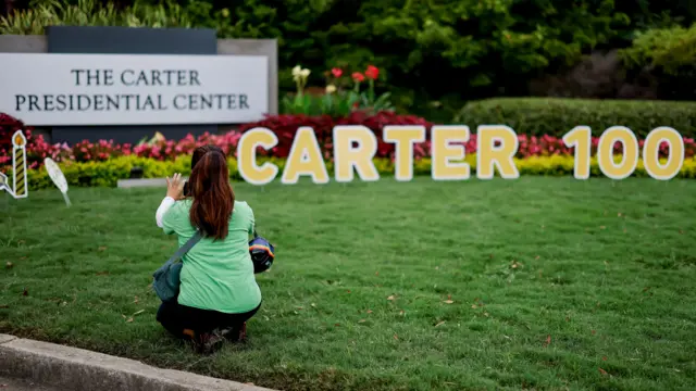 A visitor takes a photo of a sign placed at the entrance to the The Carter Presidential Center on the 100th birthday of former US president Jimmy Carter in Atlanta, Georgia, USA, 01 October 2024