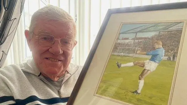 Don Murray holds a painting of a much younger self playing for Cardiff City