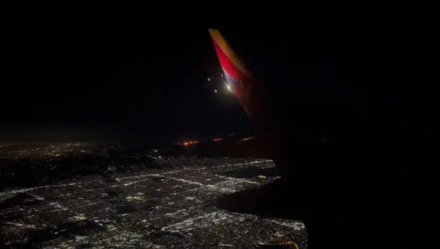 City lights and flames can be seen from a plane window