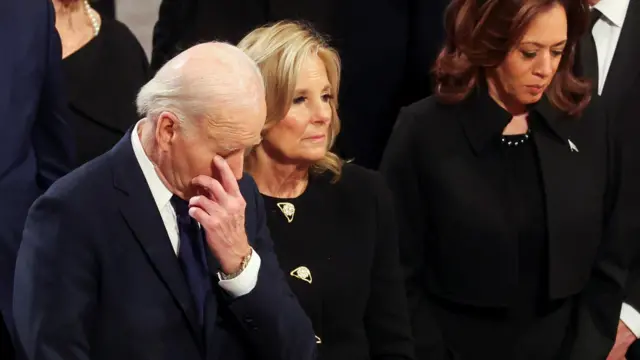 President Joe Biden with his head bowed reacting to the service