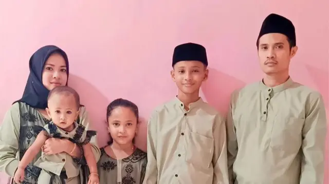 Family photo with Imron and Haikal, with the five family members posing against a pink background