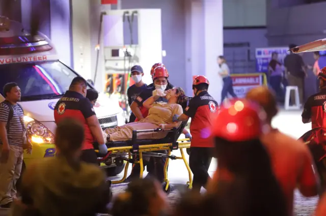 Paramedics carry a woman on a gurney