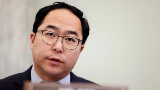 A man with glasses, a shirt and black jacket
