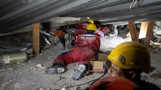 Rescuers crouching on the ground amid the debris