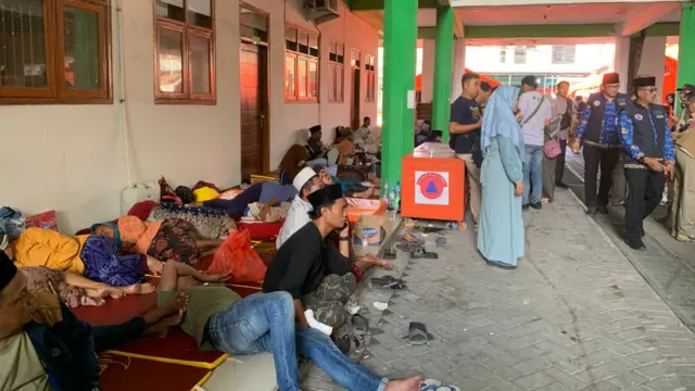 People sitting and resting on mats on the ground in a building