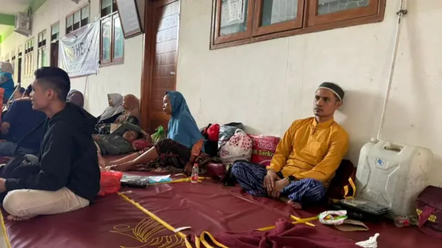 Imron in yellow long-sleeved shirt sitting on a mat on the floor