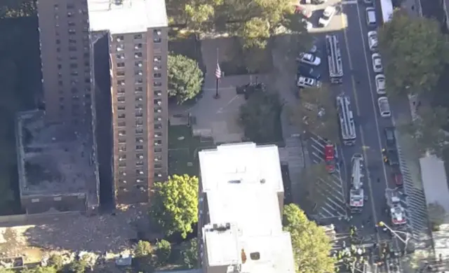 The structure where a chimney partially collapsed from the side of a building is seen in bird's eye view. The chimney, seen in the first picture, is now nowhere to be seen. Beside, there appears to be smoke and detritus