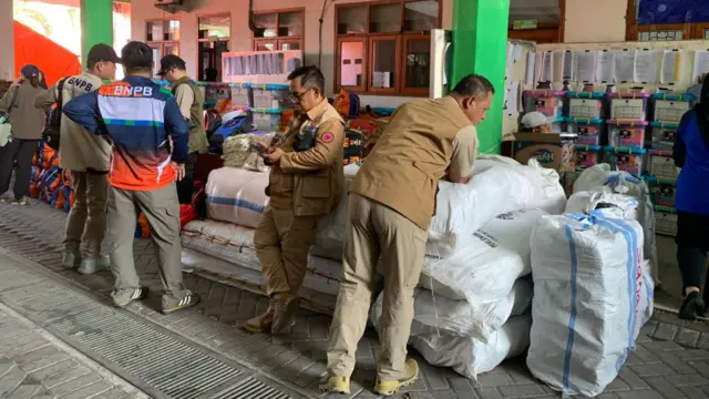 Relief workers stand around large white sacks