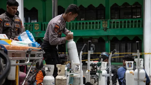 Men in uniform tending to large white canisters
