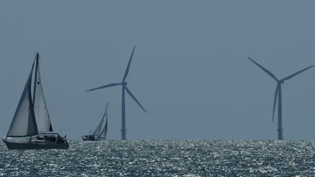 An offshore wind farm with a yacht in the foreground
