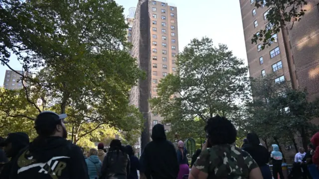 Residents look on after a gaping hole appeared on the side of the building in the Mott Haven area of the Bronx
