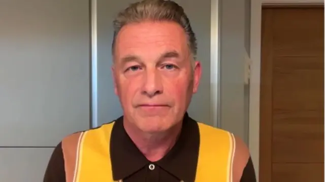 Headshot of Packham who looks solemn as he stares into the camera