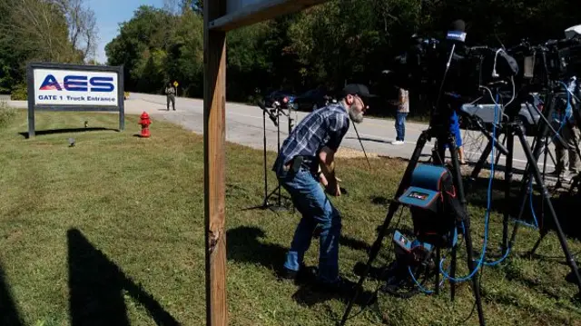 A man sets up cameras by a sign