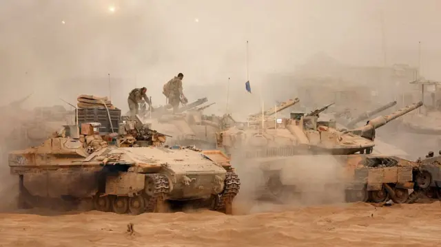 Israeli army infantry-fighting vehicles deploy next to main battle tanks at a position along the Israel-Gaza border fence