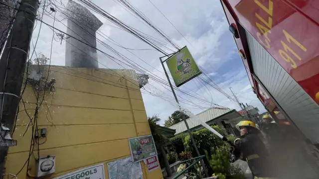 A fireman spraying water from a hose at the top of a wall