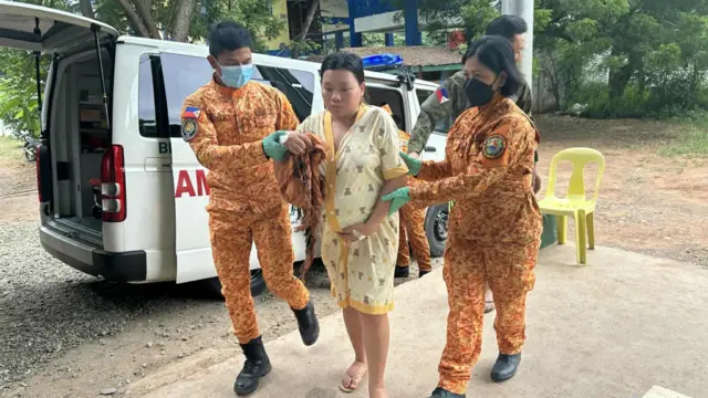 a pregnant woman getting escorted by two emergency workers