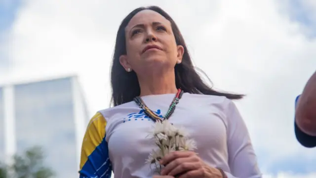Headshot of Machado holding white flowers to her chest